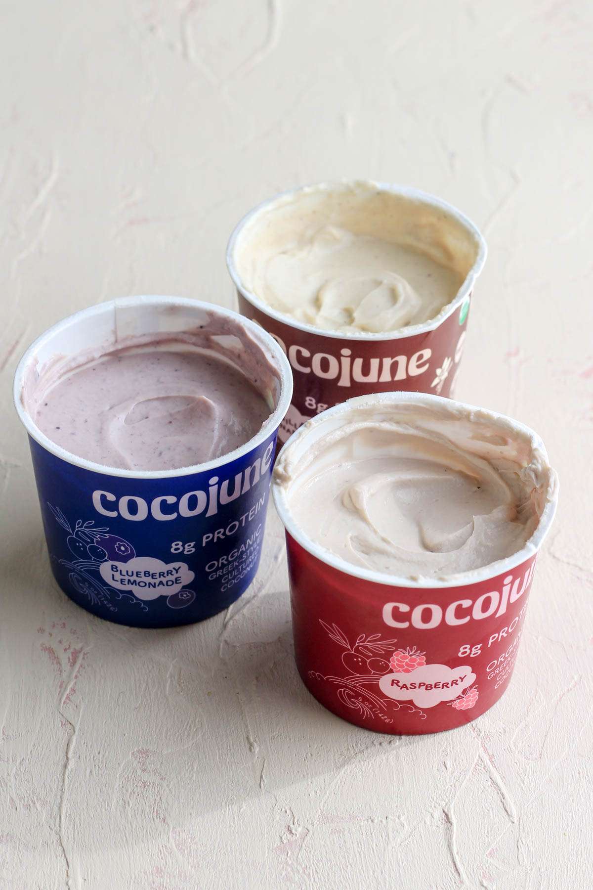 Three cocojune cartons with the lids off in a small cluster on a cream counter.
