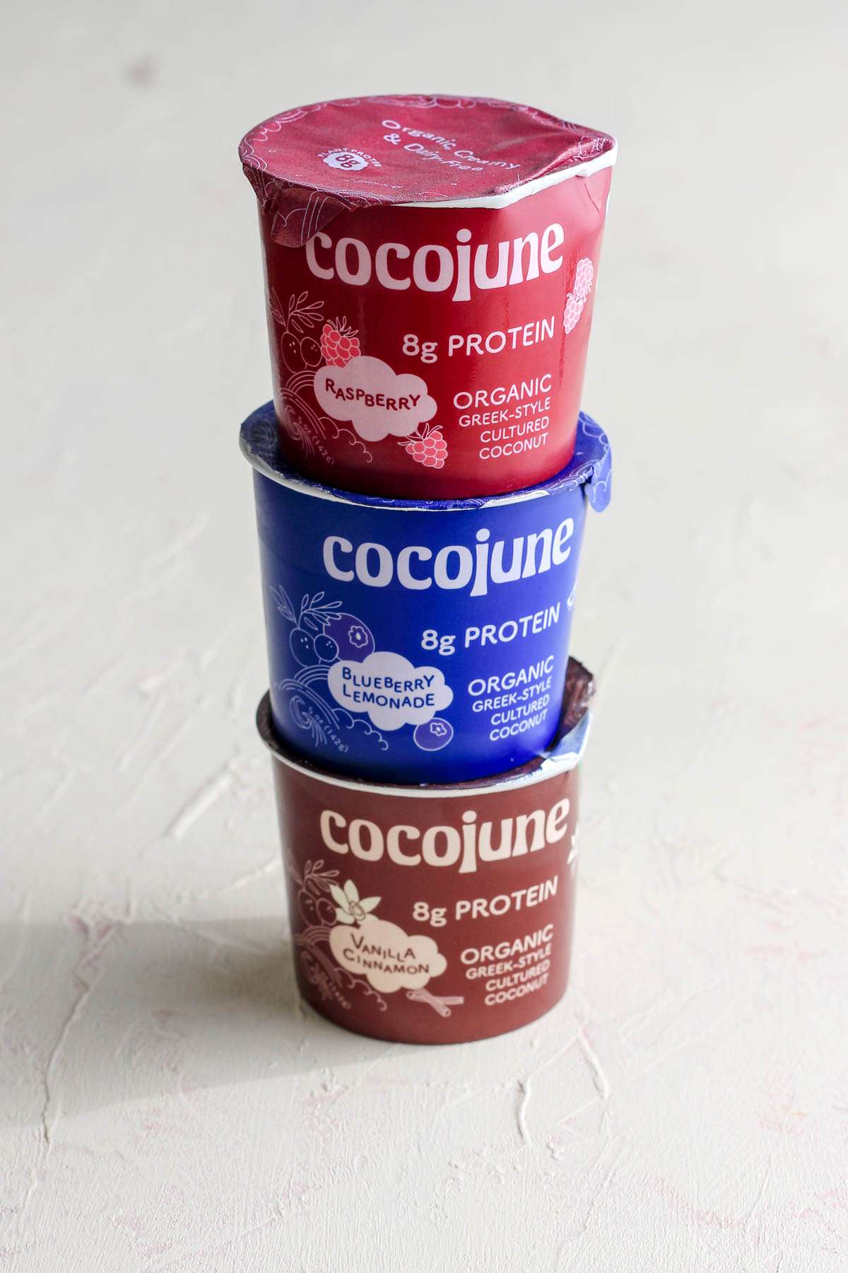 Three yogurt cartons stacked on top of each other on a cream counter.