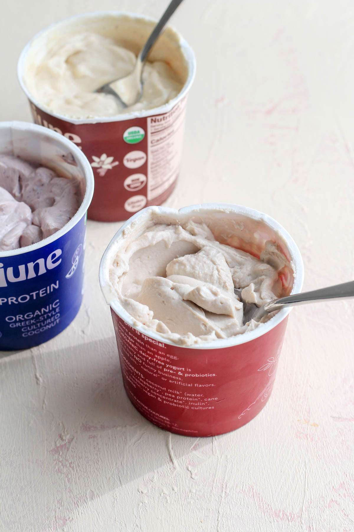 Silver spoons in the greek yogurt cartons on a cream counter.