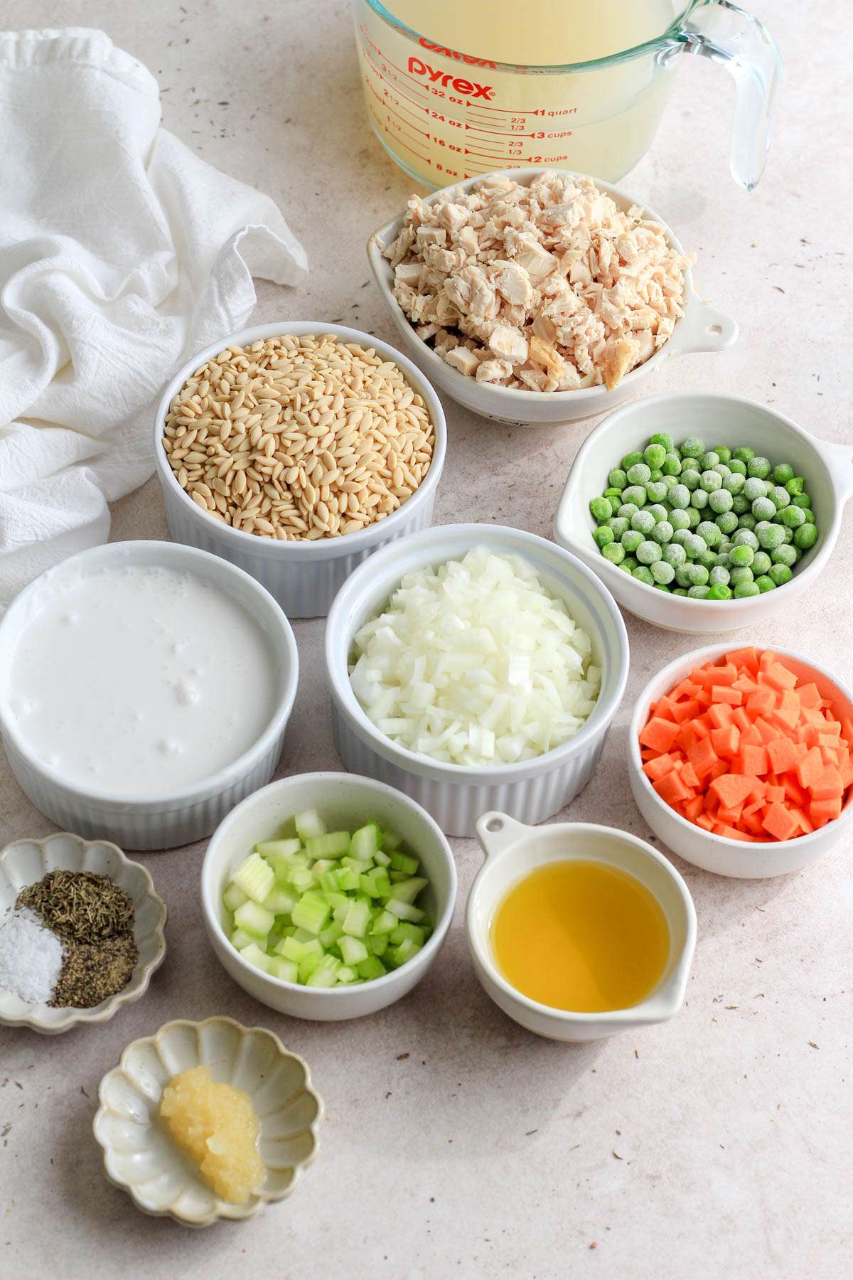 Ingredients for dairy free chicken pot pie orzo on a tan counter.