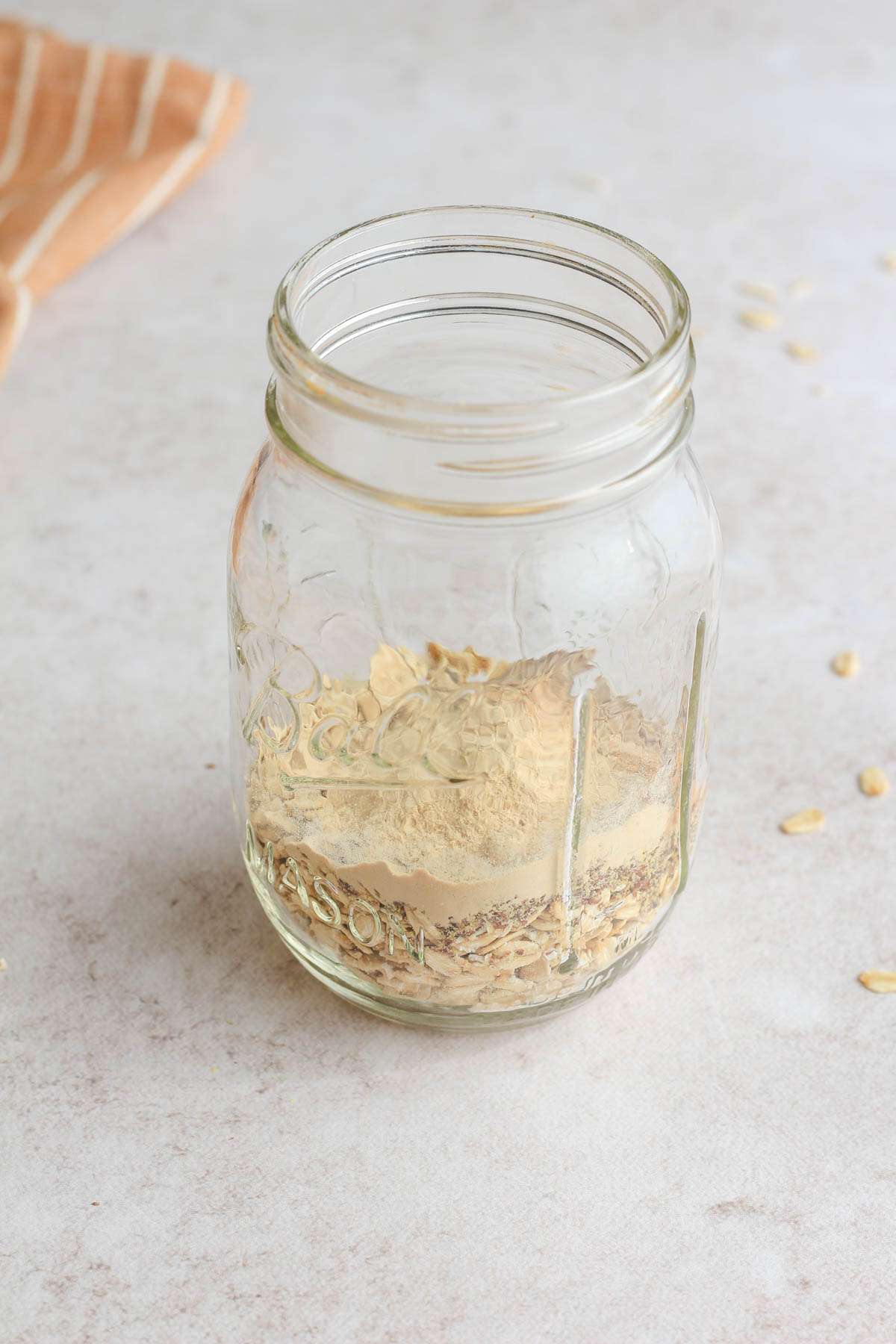A mason jar with dry ingredients for peanut butter lactation overnight oats.