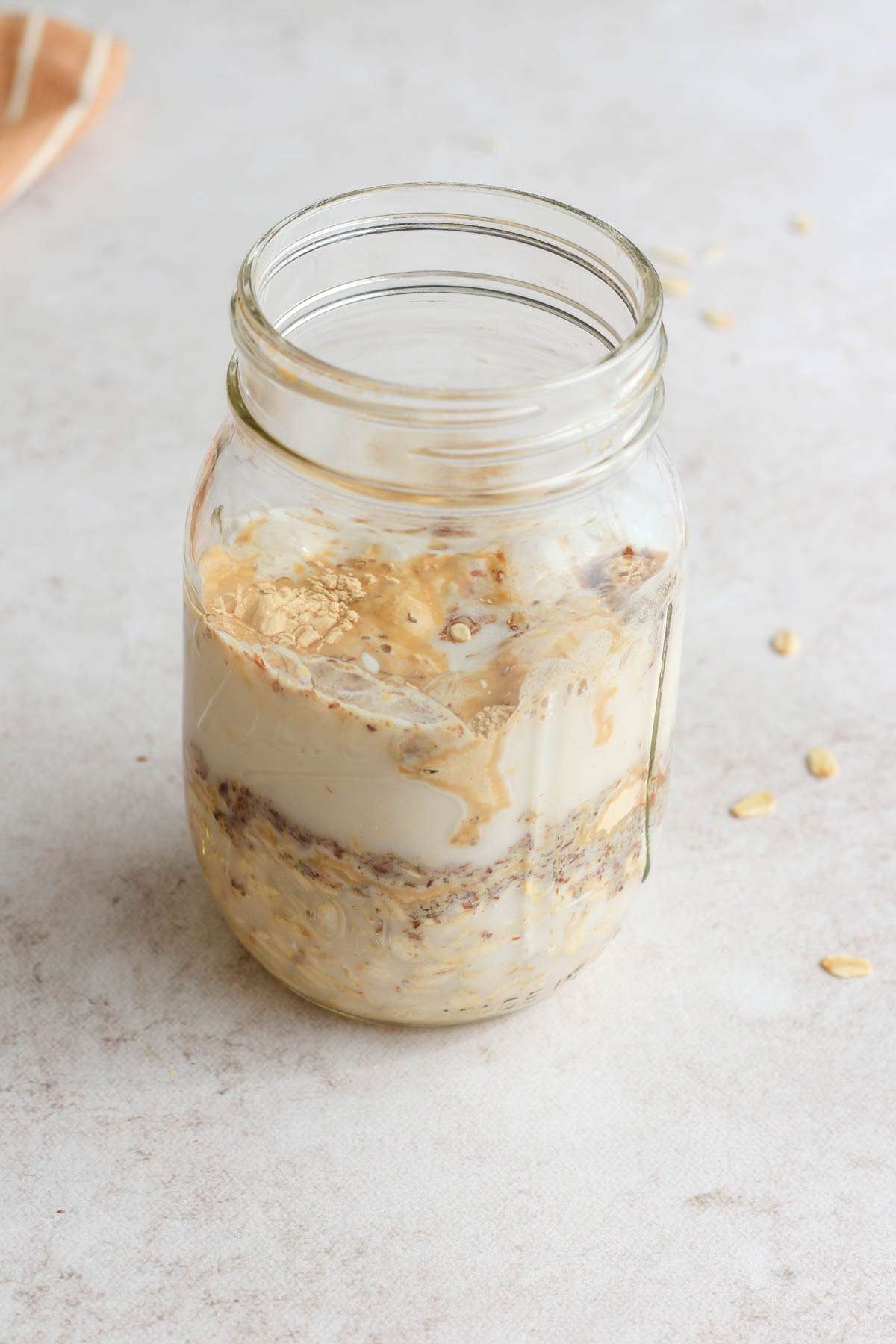 A mason jar with the ingredients for peanut butter chocolate chip lactation overnight oats before mixing.
