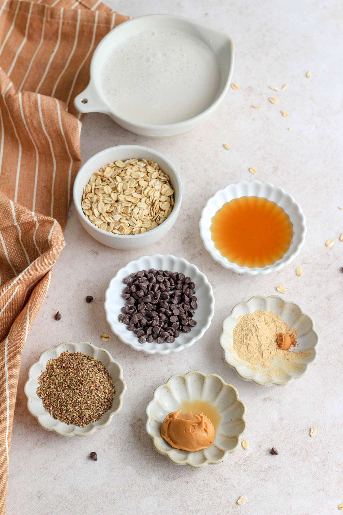 Small white dishes with the pre-measured ingredients for vegan lactation overnight oats.