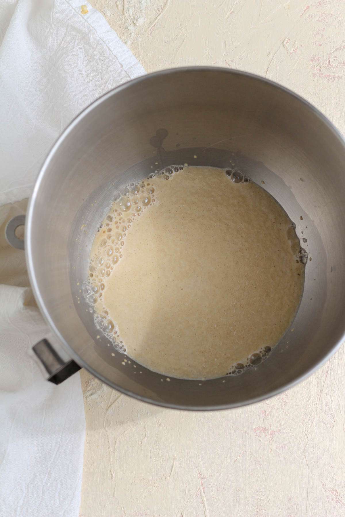 A silver mixing bowl with yeast activated.