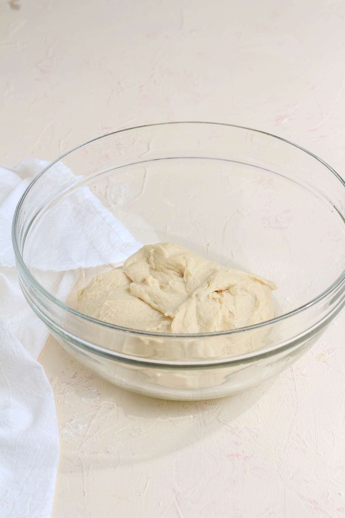 A glass bowl with a small lump of vegan bread dough before rising.