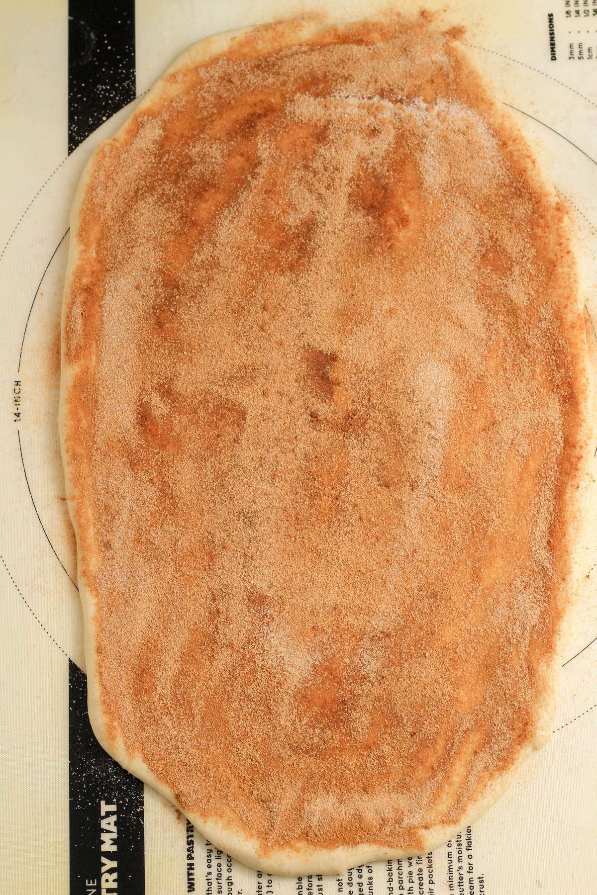 Rolled out vegan bread dough with a cinnamon sugar layer.