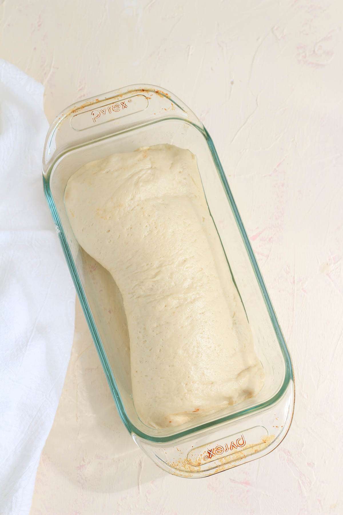 A glass bread loaf with the rolled up cinnamon swirl bread before rising.