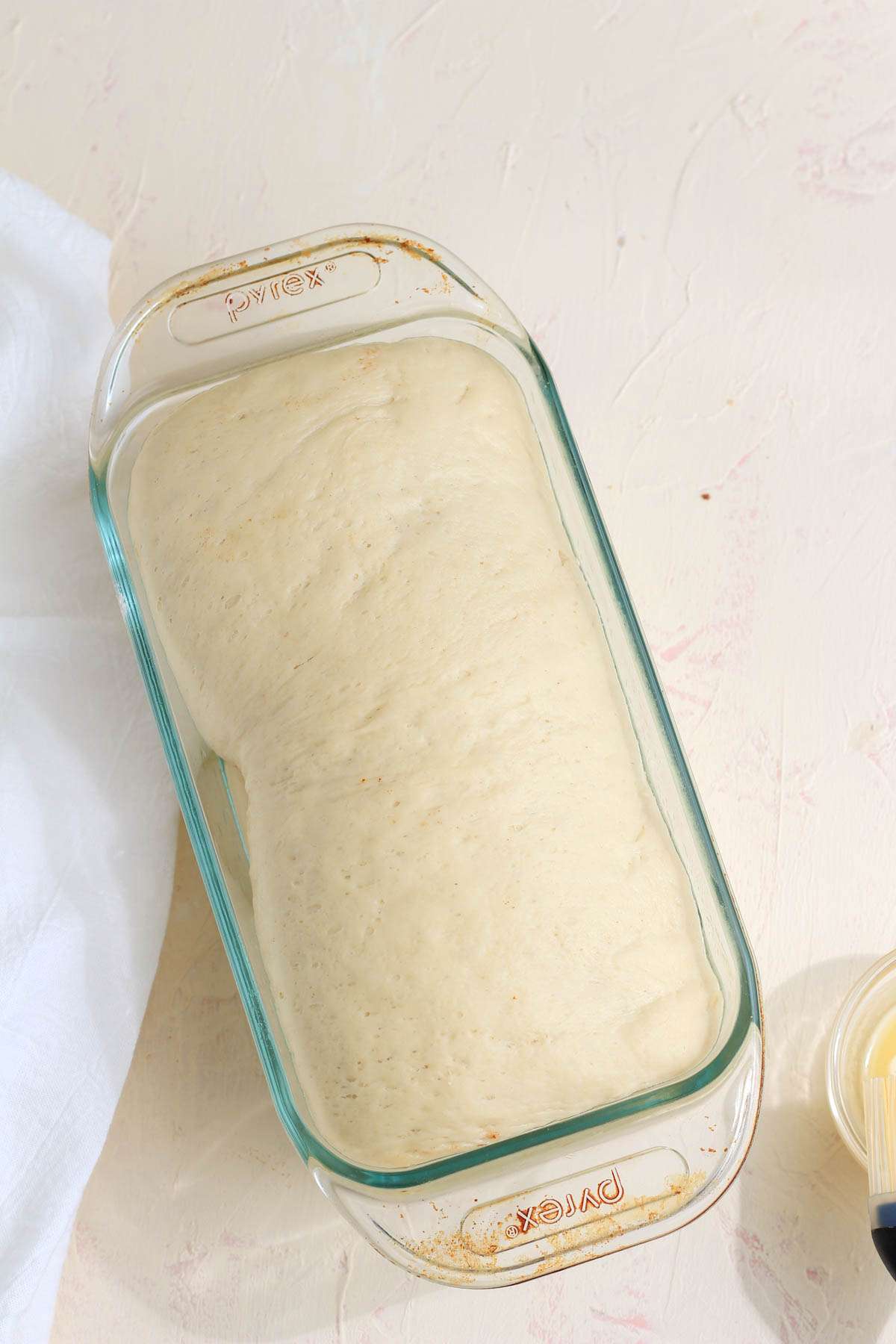 A glass bread loaf with the vegan cinnamon swirl dough after rising.