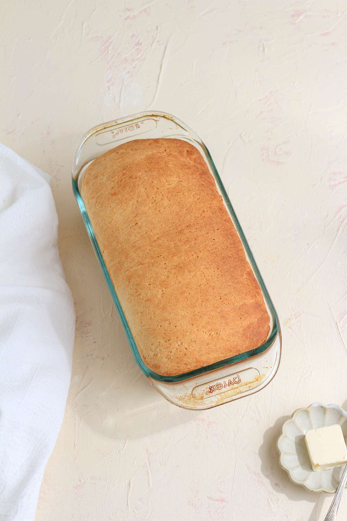 A glass loaf pan with a loaf of vegan cinnamon swirl bread after baking.