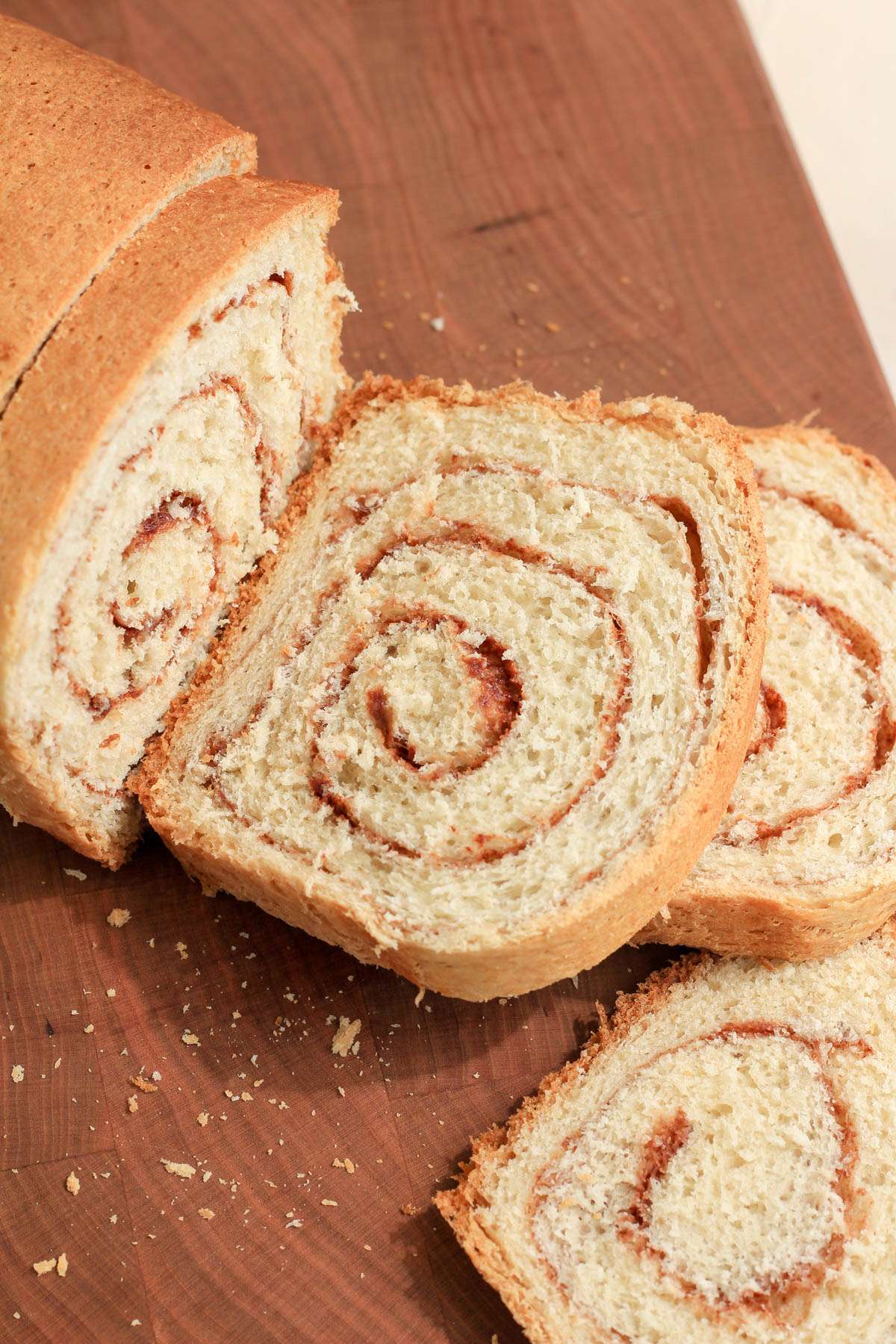 A wooden cutting board with slices of vegan cinnamon swirl bread.