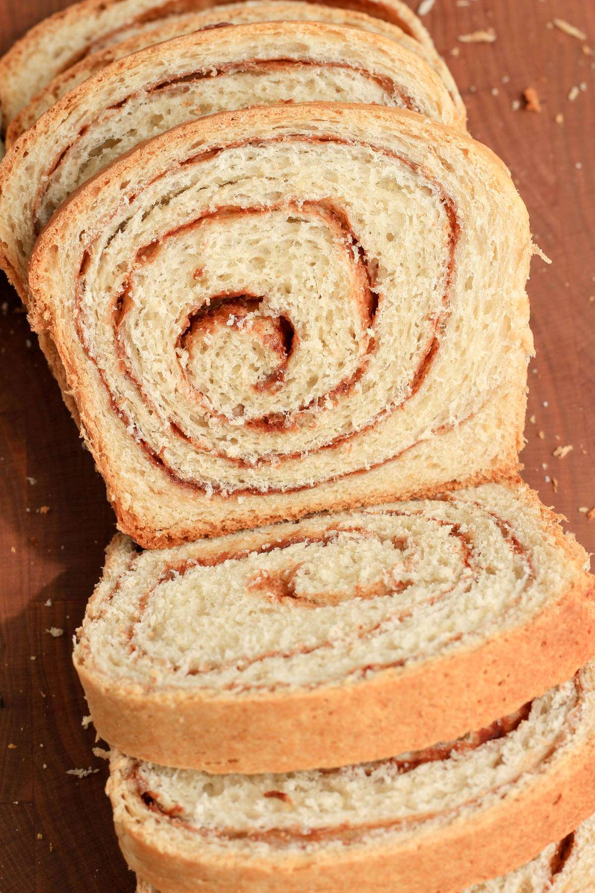 Top down image of slices of vegan cinnamon swirl bread on a wooden cutting board.