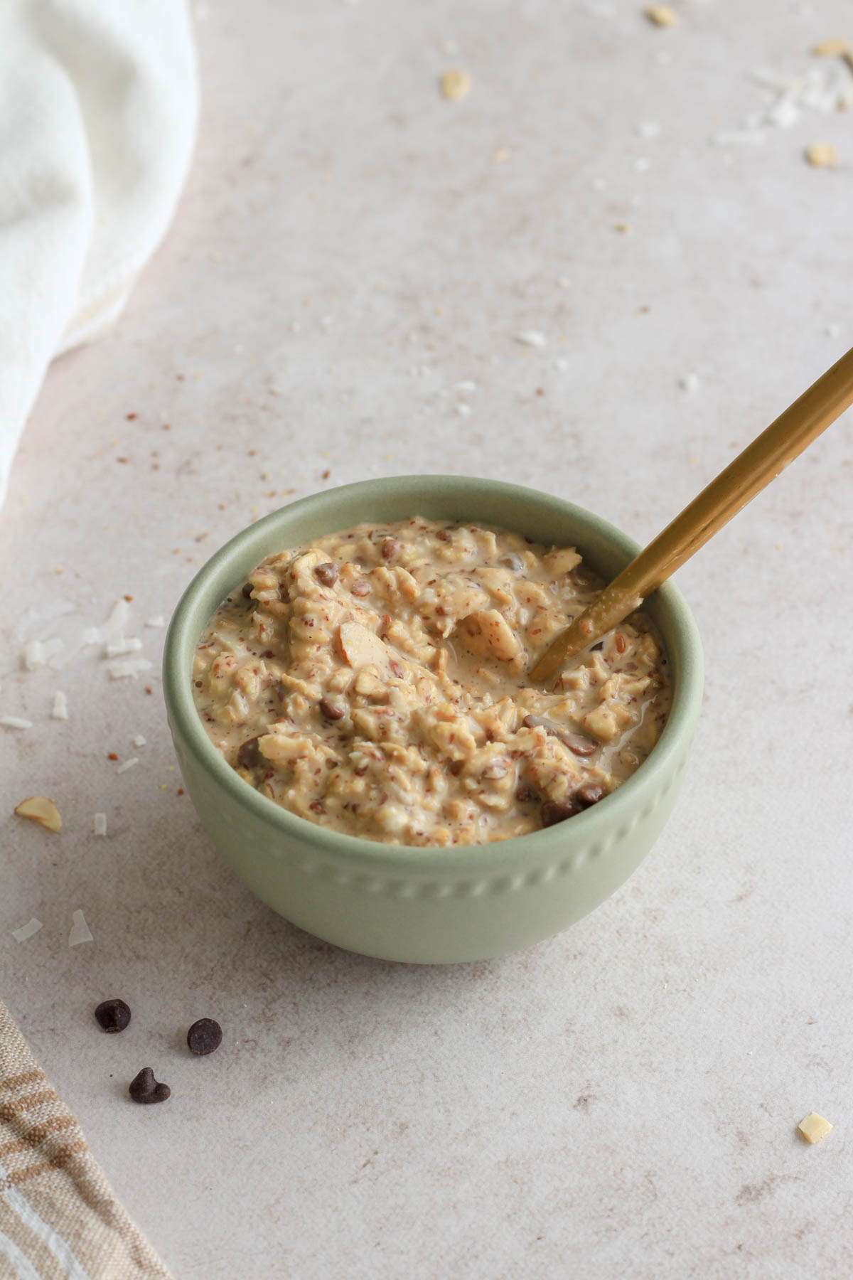 A small green bowl with almond joy lactation overnight oats with a gold spoon sticking out.