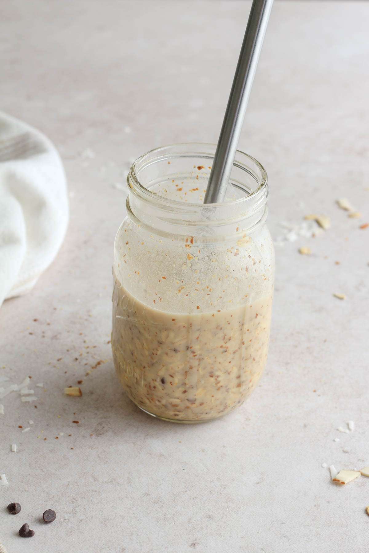 A small metal whisk in a glass mason jar with almond joy lactation overnight oats.