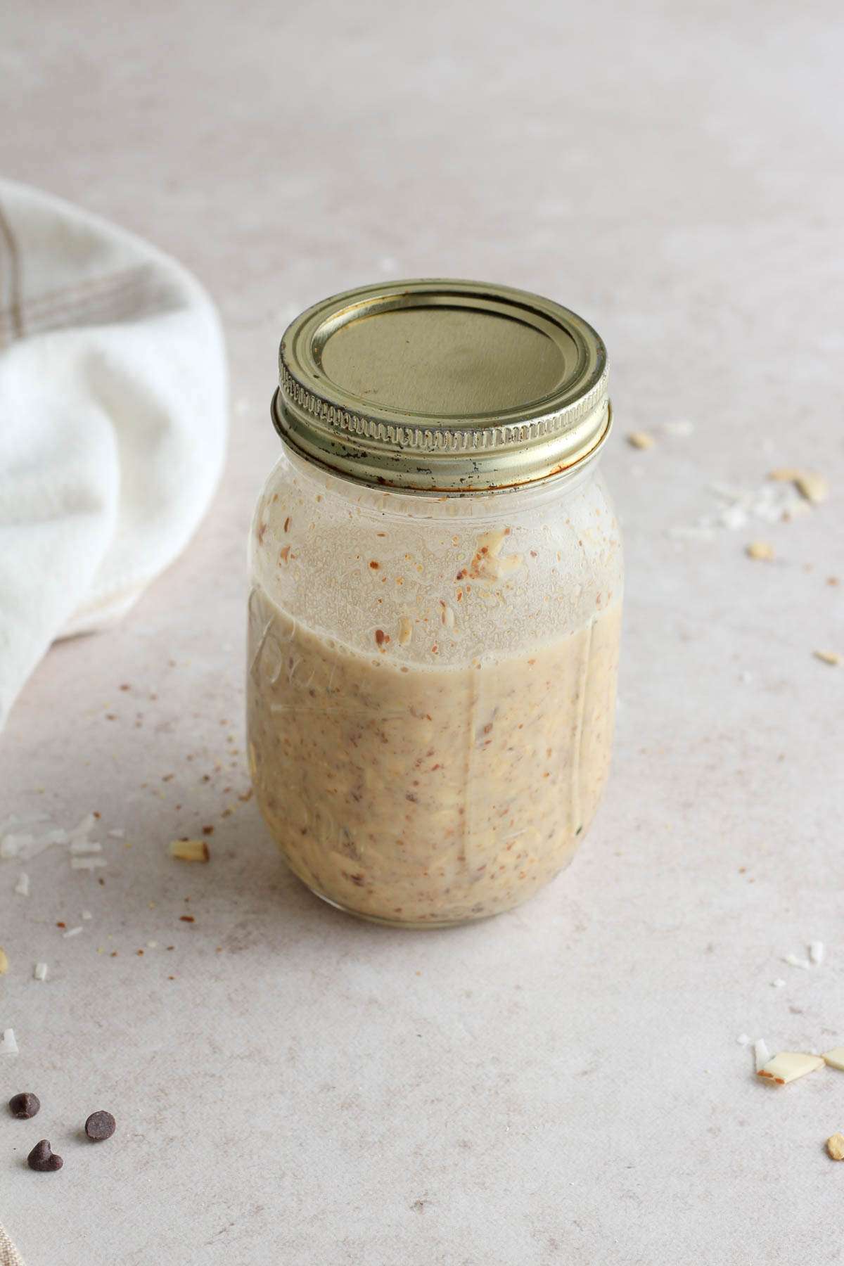 A lidded glass mason jar of overnight oats before going into the fridge.