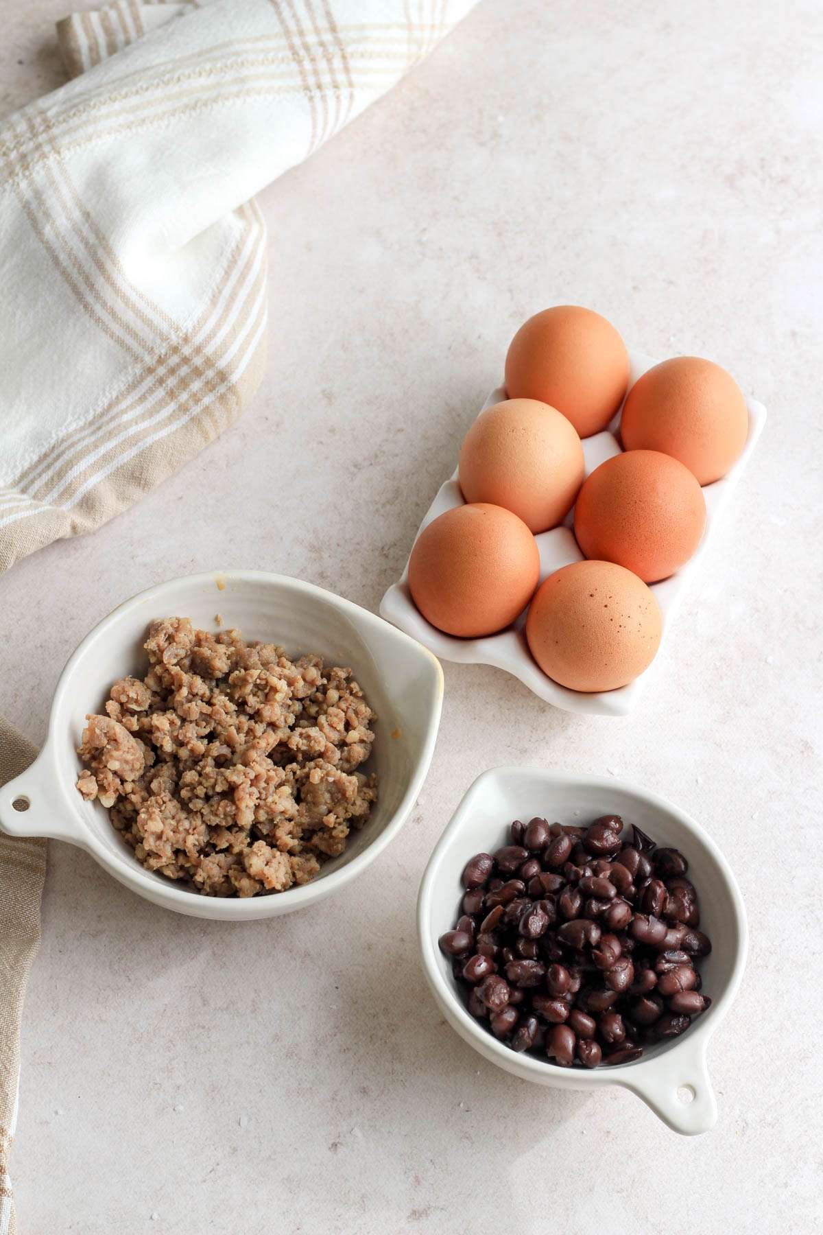 Ingredients for egg and black bean scramble on a tan counter.