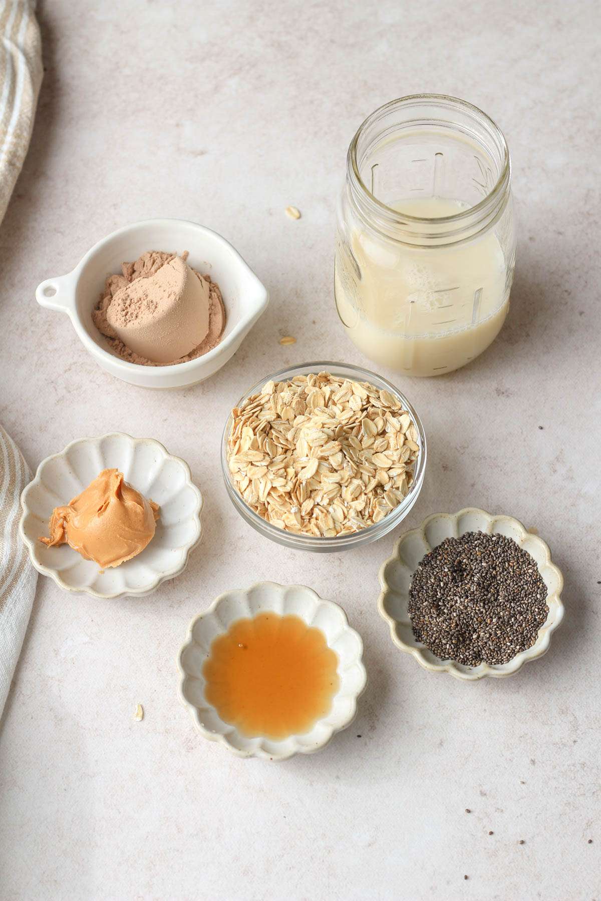 Ingredients for chocolate peanut butter overnight oats on a tan counter.