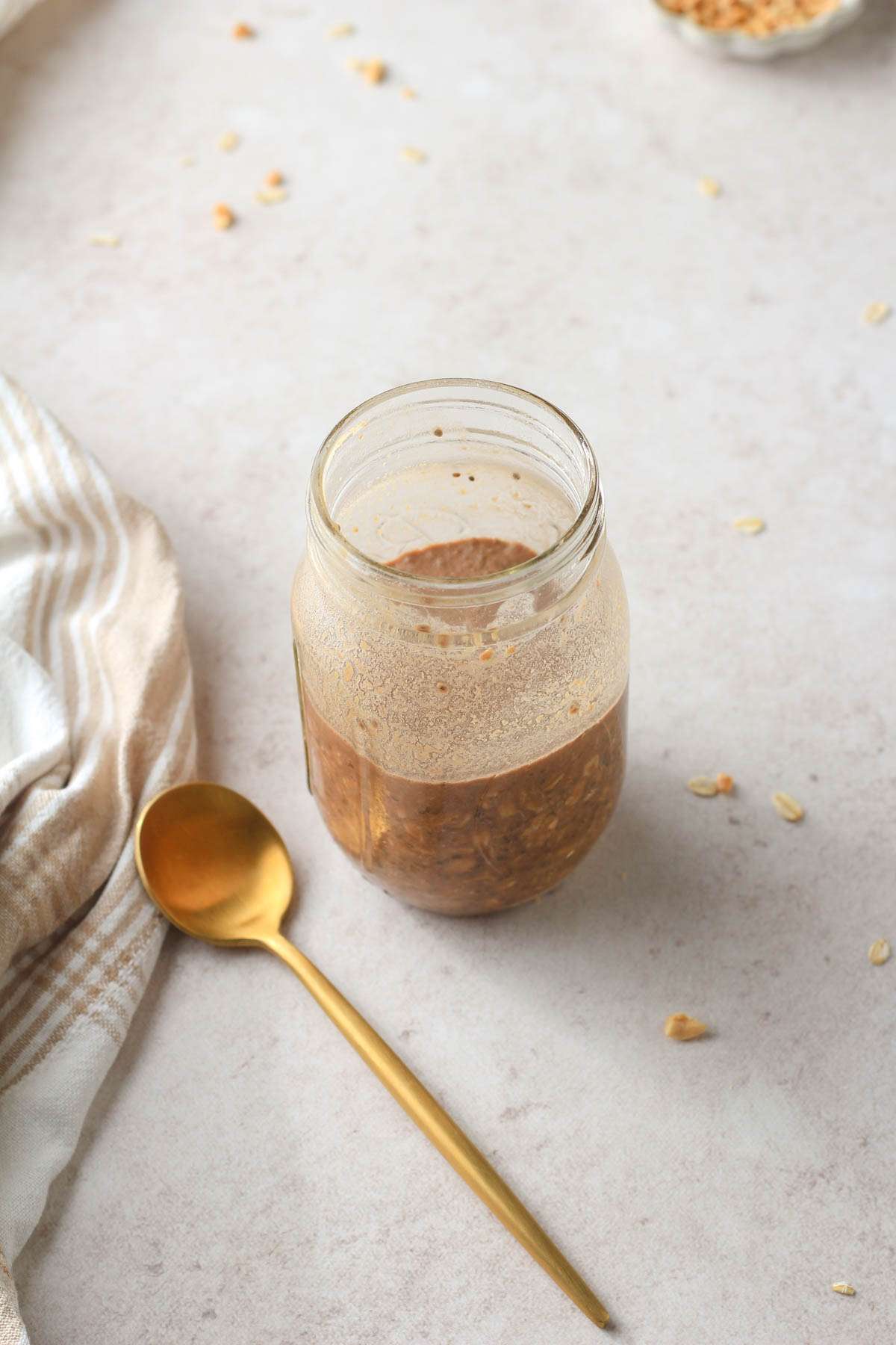 A glass mason jar of chocolate peanut butter overnight oats after refrigerating overnight.