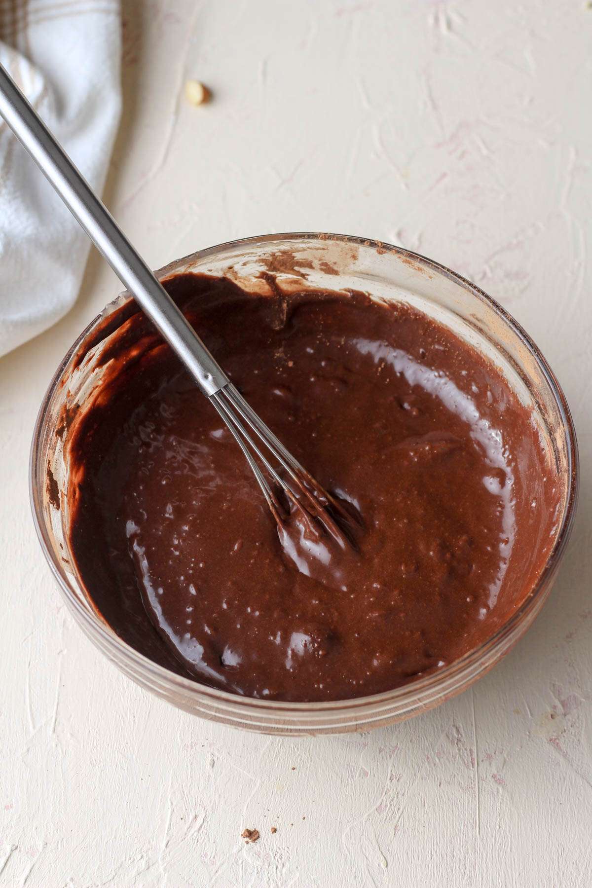 Chocolate sweetened condensed oat milk mixed with a whisk in a small glass bowl.
