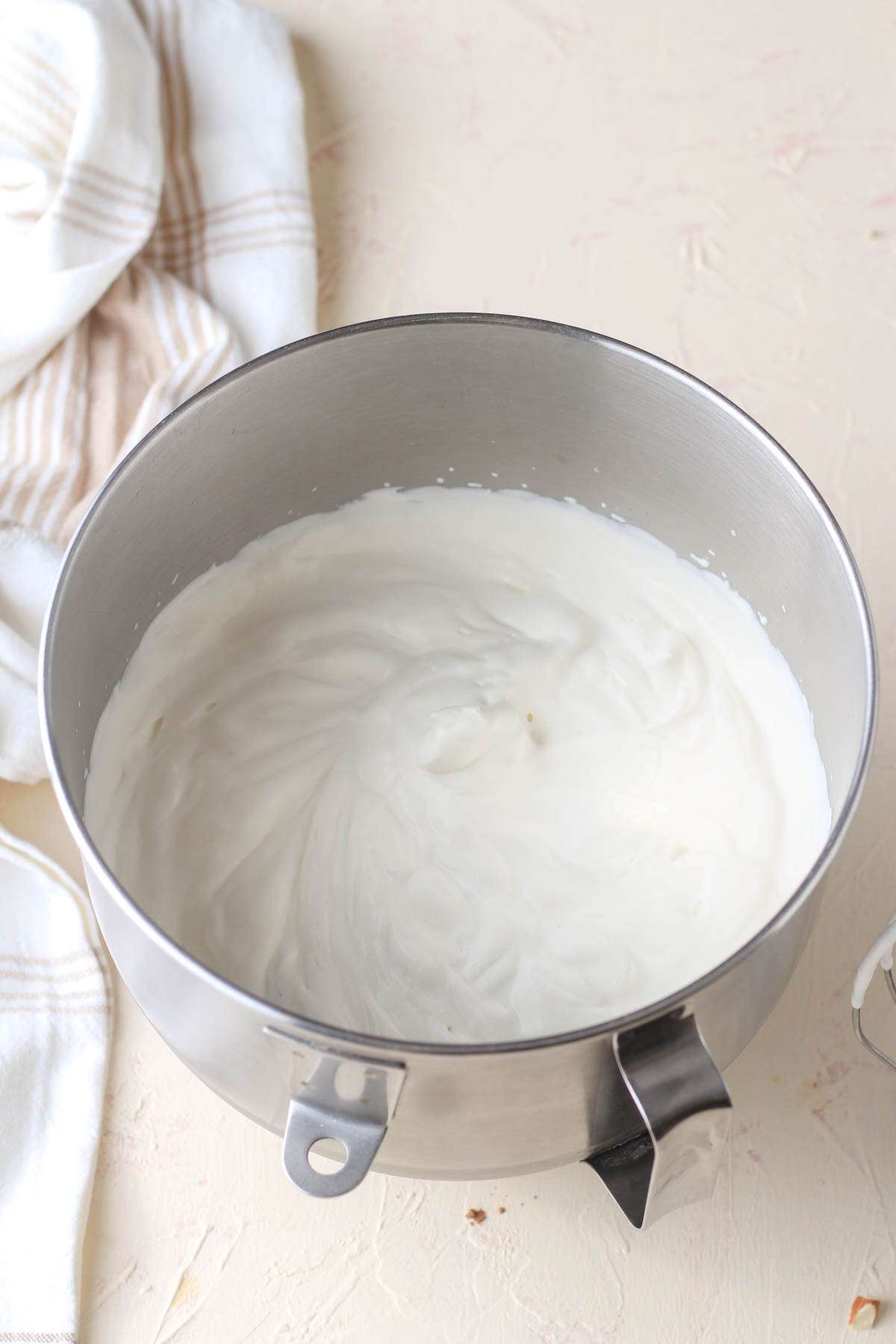 A silver mixing bowl with whipped dairy free heavy whipping cream.
