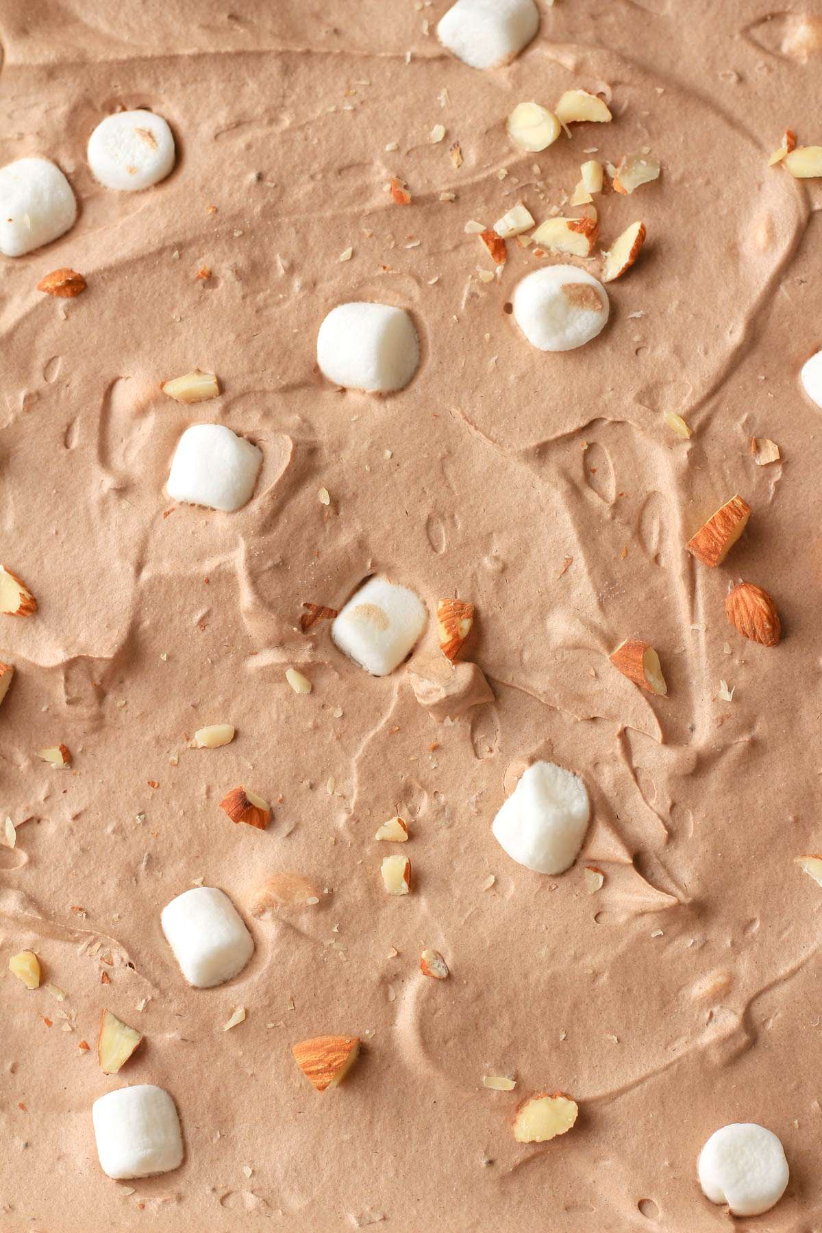 A close up of dairy free rocky road ice cream topped with marshmallows and chopped almonds.