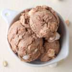 Three scoops of rocky road ice cream in a white bowl.