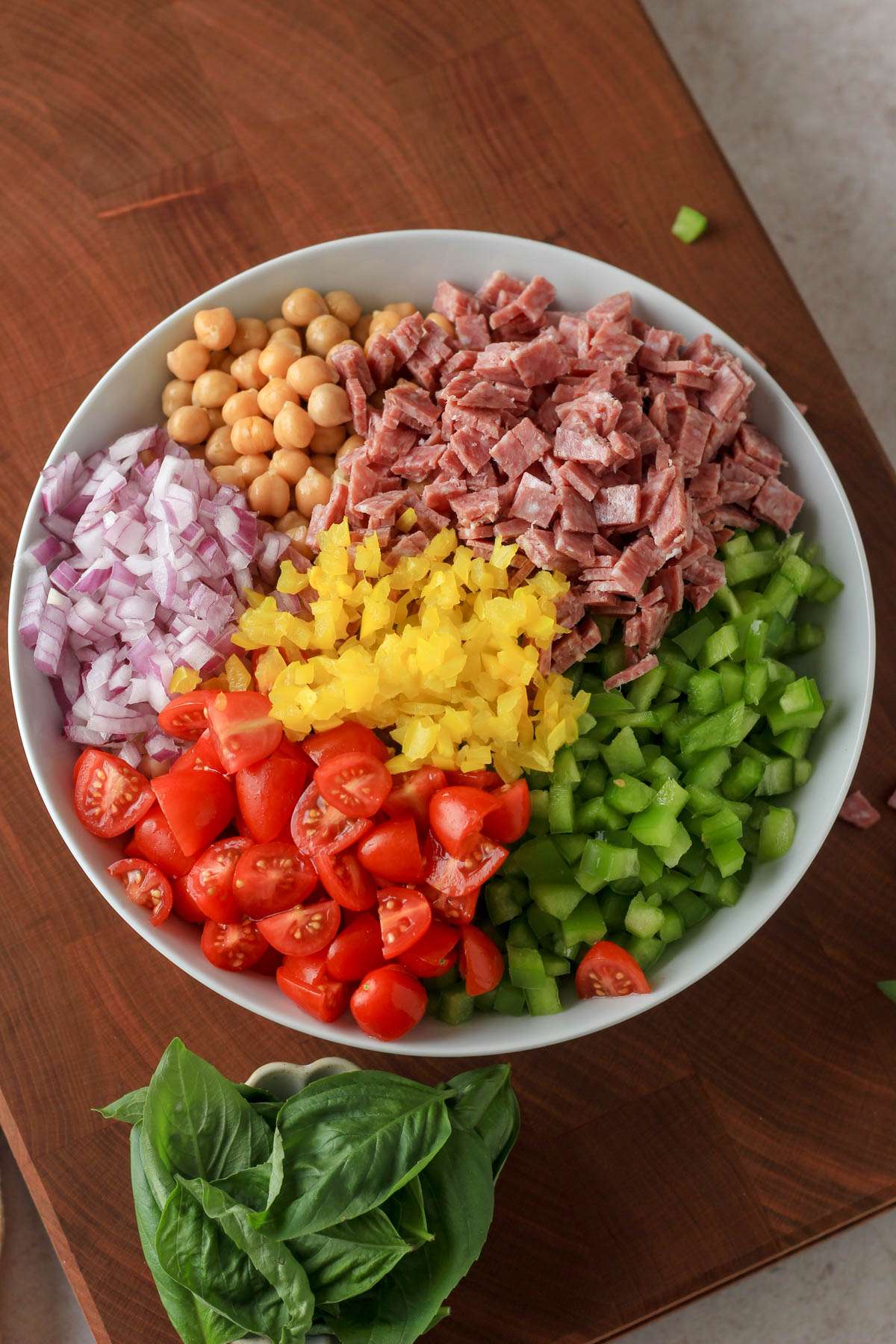 A white bowl with the ingredients for Italian grinder bean salad before mixing and adding dressing.